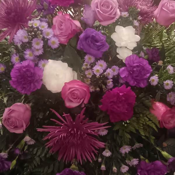 Purple and pink floral arrangement with roses and daisies