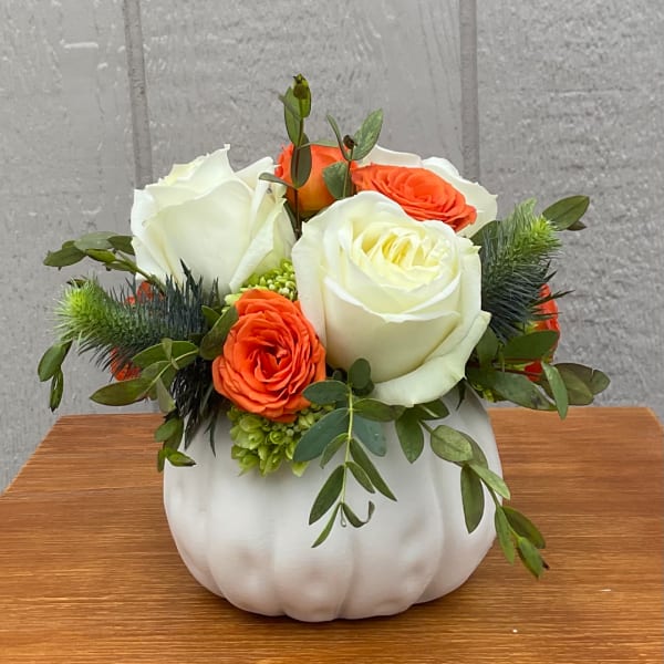 White and orange roses arranged in a white pumpkin vase