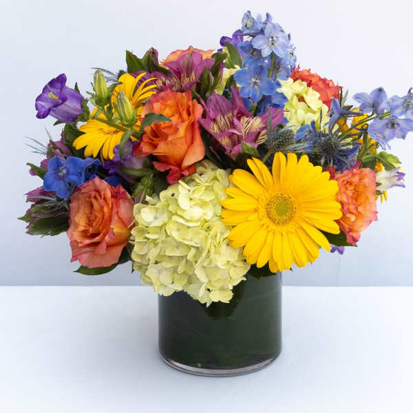 Mixed bouquet of roses, hydrangea, and daisies in a dark glass vase