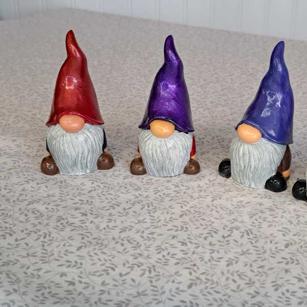 Four painted gnome figurines with tall hats on a patterned surface