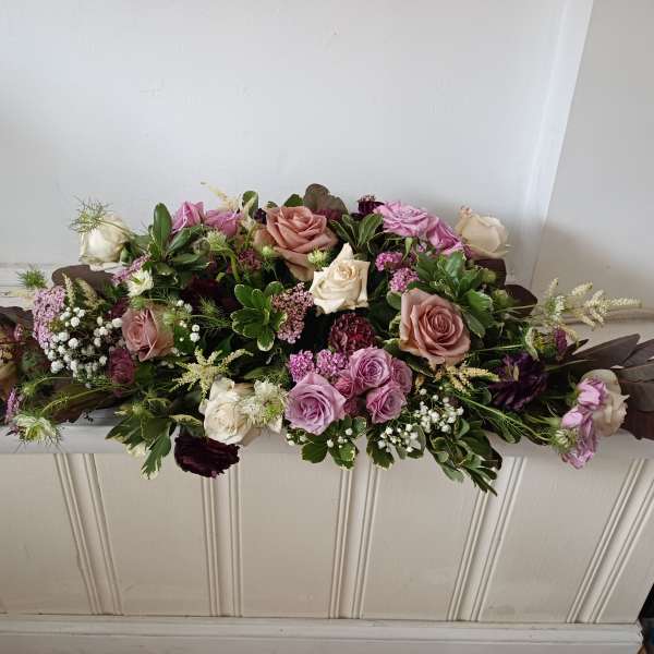 Low floral arrangement with pink and cream roses on a white surface