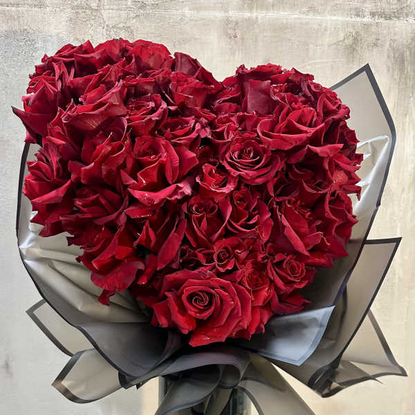 Bouquet of red roses wrapped in black paper with a ribbon