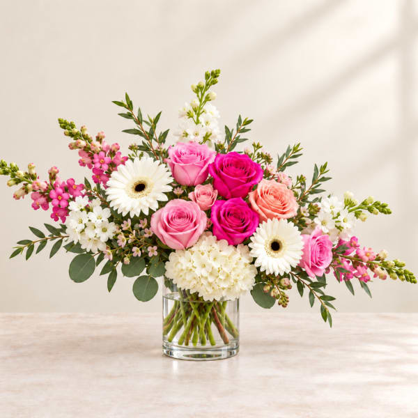Pink and white roses with gerbera daisies in a clear glass vase