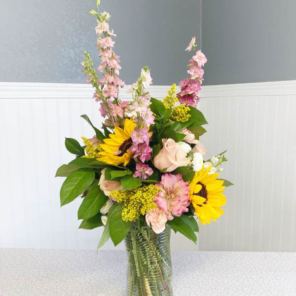 Mixed bouquet with sunflowers, pink blooms, and a glass vase