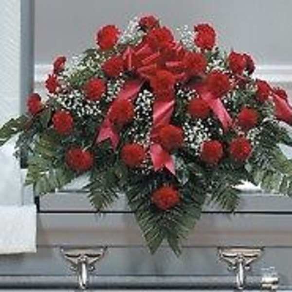 Red floral casket spray with greenery on a gray casket