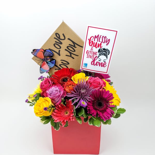 Colorful mixed flower arrangement in a red box with a card and butterfly decoration