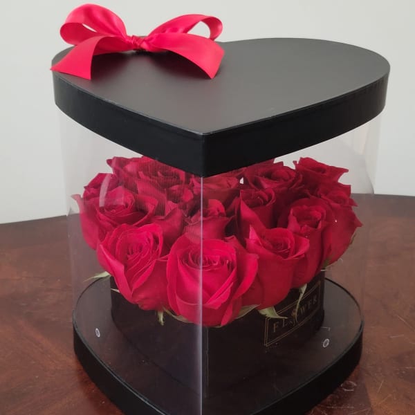 Heart-shaped box of red roses with a pink ribbon bow