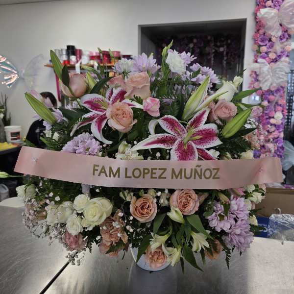 Large pink and white floral arrangement with a memorial ribbon