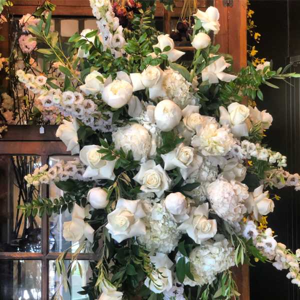 Large white floral arrangement with roses, peonies, and orchids