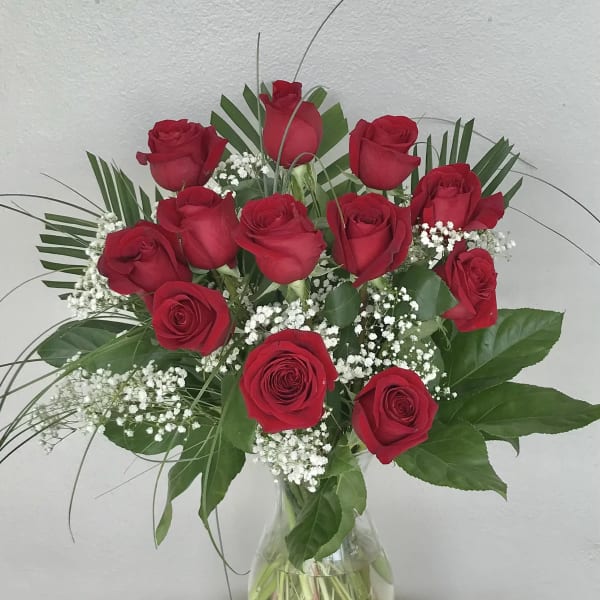 Red roses arranged in a clear glass vase with baby's breath