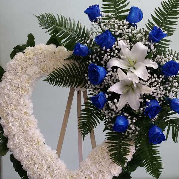 White floral wreath and star-shaped arrangement with blue roses and lilies
