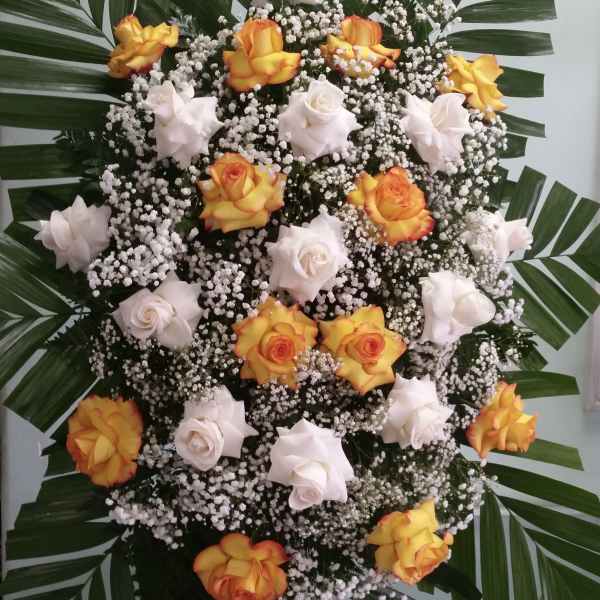 Standing floral spray with orange and white roses and palm leaves