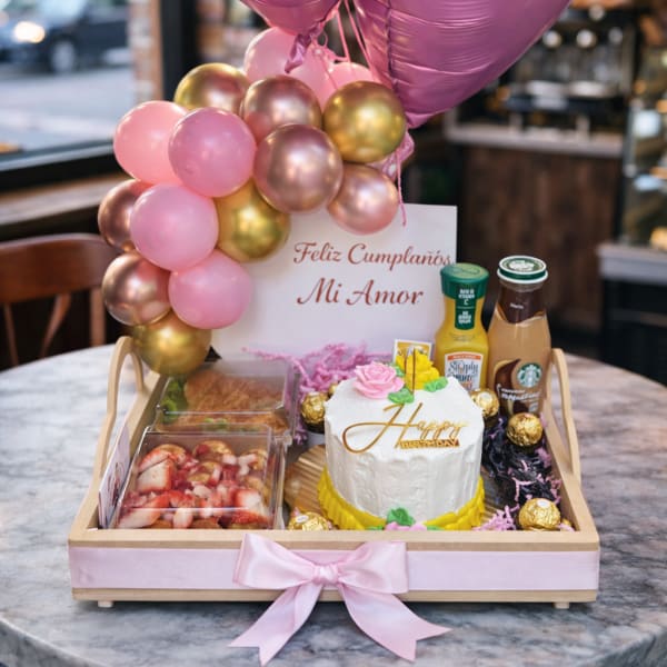 Birthday gift tray with pink heart balloons, cake, and snacks