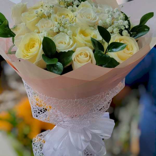 Bouquet of pale yellow roses with white filler flowers and a white ribbon