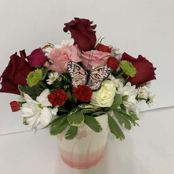 Mixed bouquet in a pink vase with a butterfly decoration