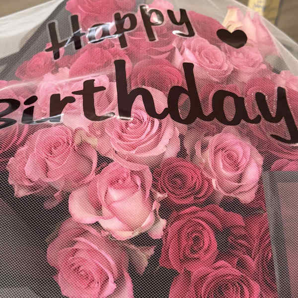 Pink roses in a black box under a mesh cover with birthday text