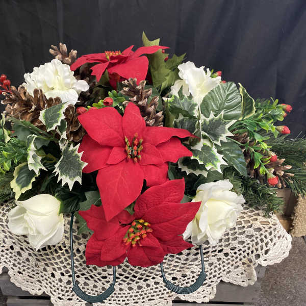 Holiday floral arrangement with red and white poinsettias and pinecones