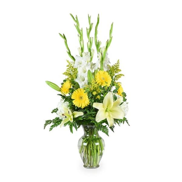 Yellow and white flowers arranged in a clear glass vase