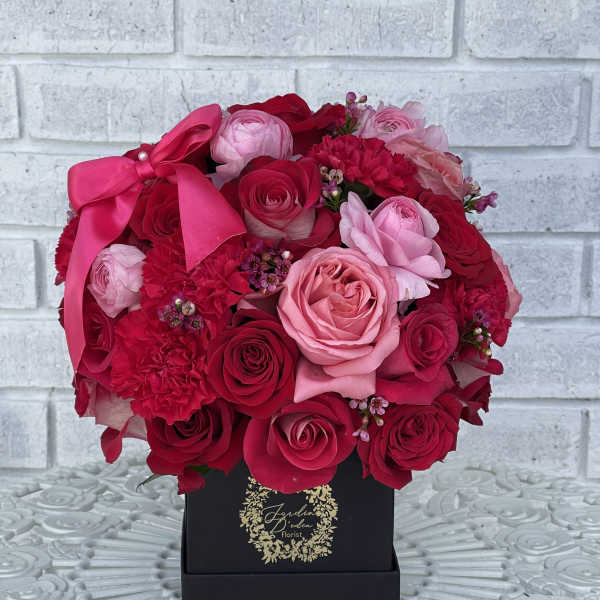 Pink and red rose bouquet in a black box with a satin bow