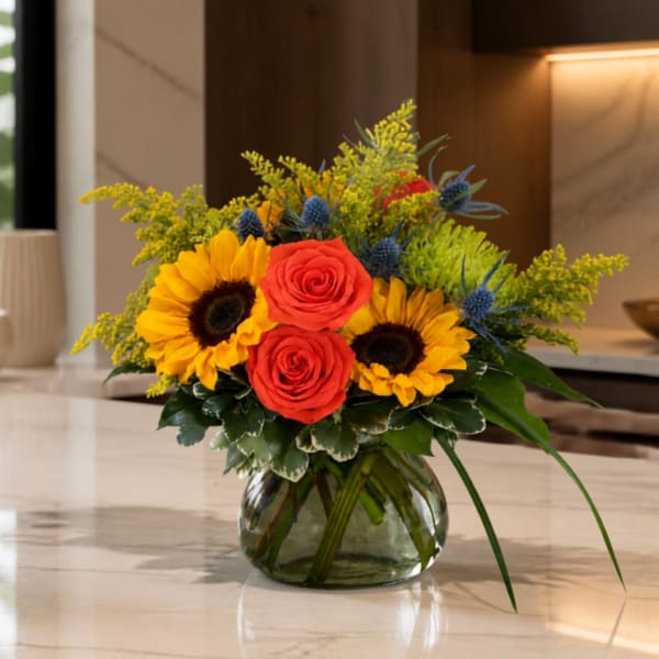Sunflowers and red roses arranged in a glass vase