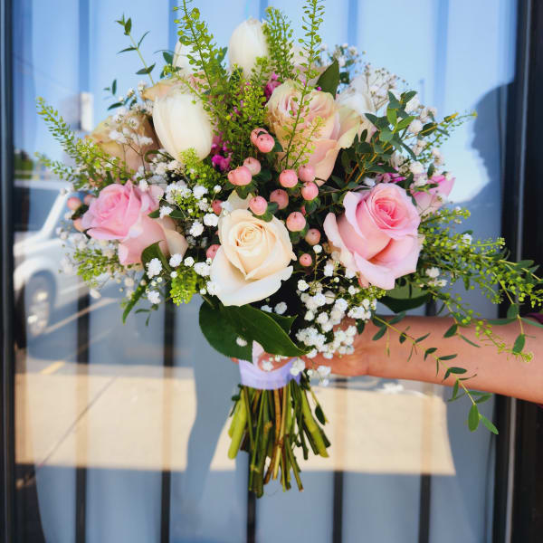 Handheld bouquet of pink and white roses with small white filler flowers