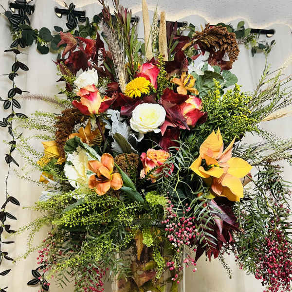 Tall mixed floral arrangement in a clear glass vase with autumn colors