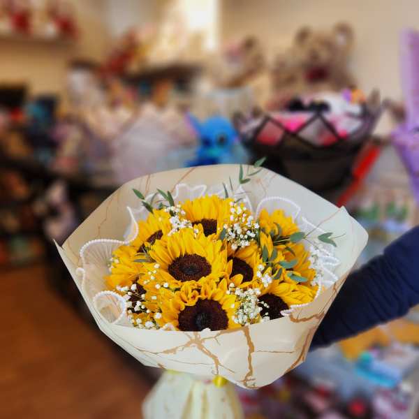 Bouquet of yellow sunflowers with white filler flowers in cream wrapping