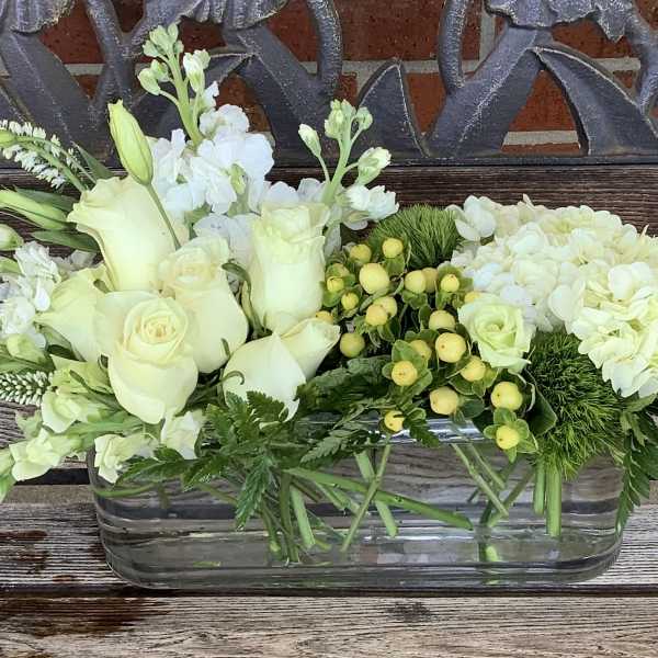 White roses and hydrangeas in a rectangular glass vase