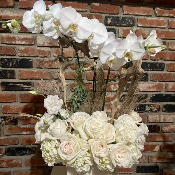 White orchids and roses arranged in a white box vase