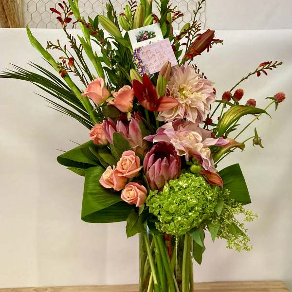 Tall mixed bouquet in a clear glass vase with pink and red blooms