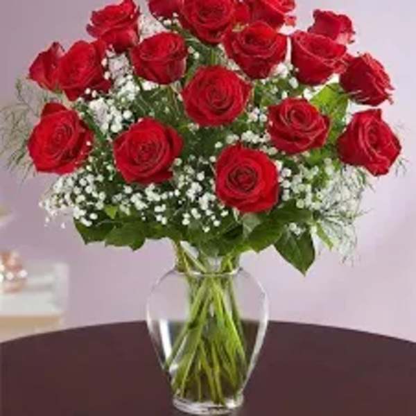Red roses arranged in a clear glass vase with white filler flowers