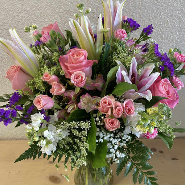 Pink roses and lilies arranged in a clear glass vase