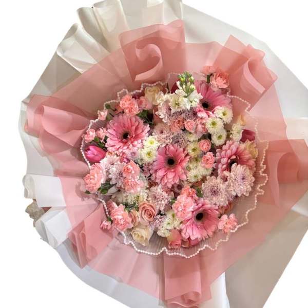Pink mixed flower bouquet wrapped in translucent pink and white paper