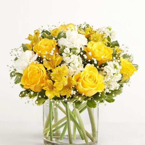 Yellow and white roses arranged in a clear glass vase