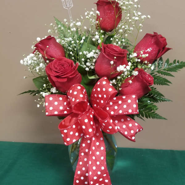 Red roses with baby's breath in a glass vase and a red polka-dot bow