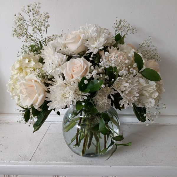 White roses and chrysanthemums in a round glass vase