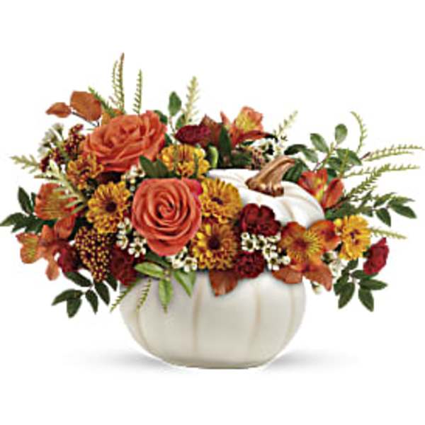 Orange and yellow floral arrangement in a white pumpkin container