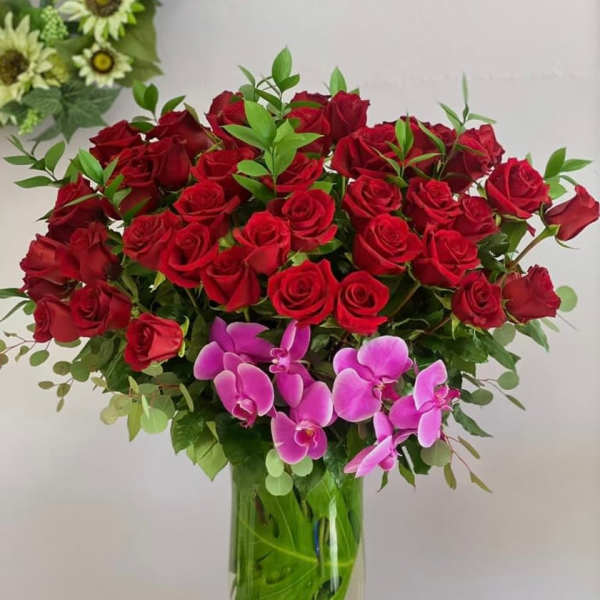 Red roses and pink orchids arranged in a glass vase