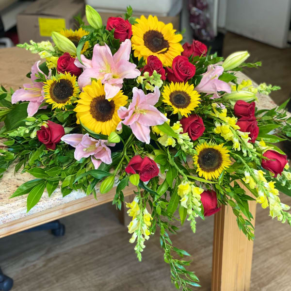 Bouquet of red roses, pink lilies, and sunflowers on a table