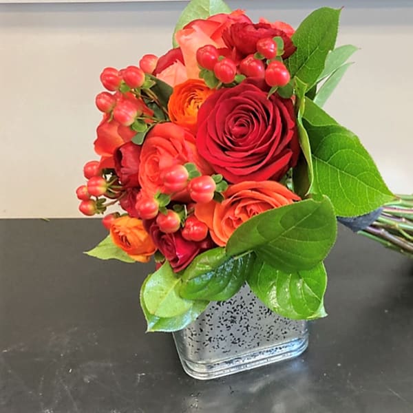 Bouquet of red and orange roses in a square glass vase