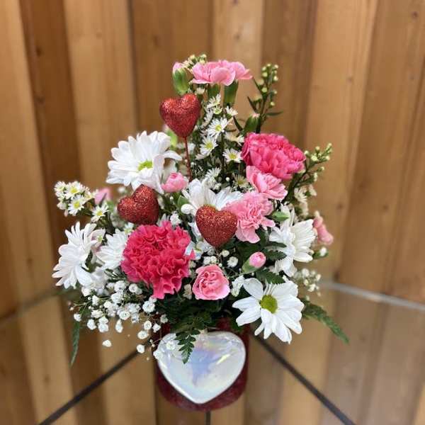 Pink and white flower arrangement with glittery red hearts in a vase