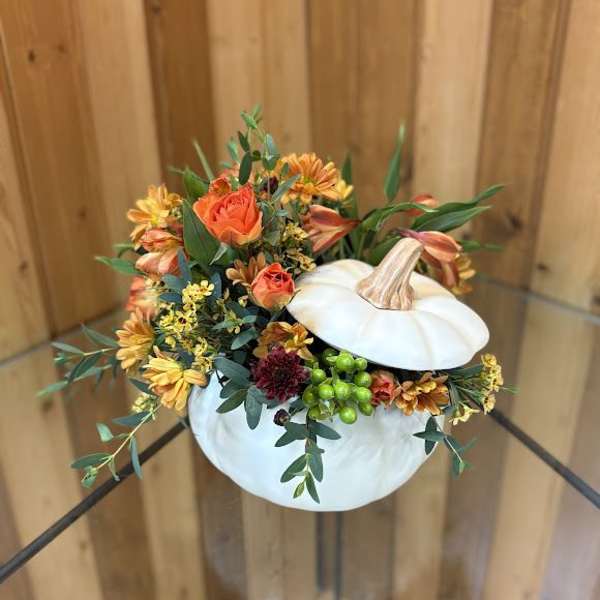 White pumpkin filled with orange flowers and greenery