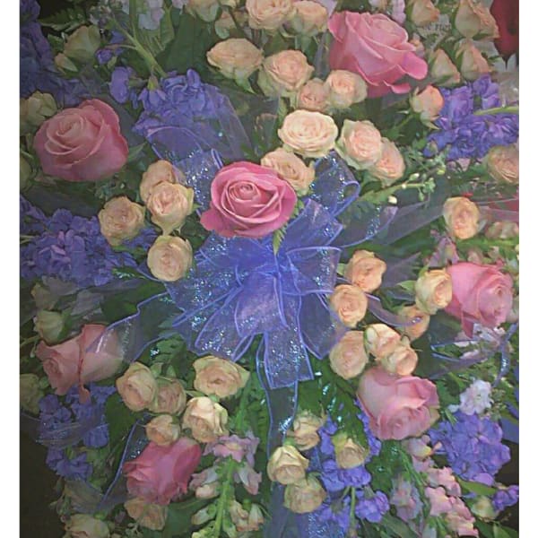 Large pink and peach rose spray with purple flowers and a blue ribbon
