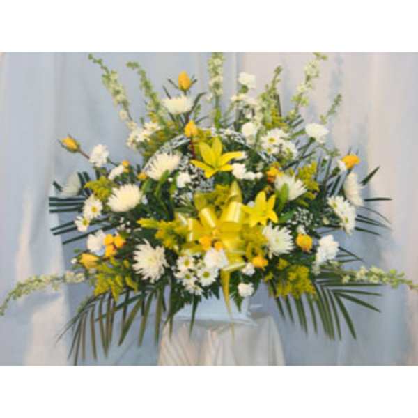 Large yellow and white floral arrangement on a pedestal