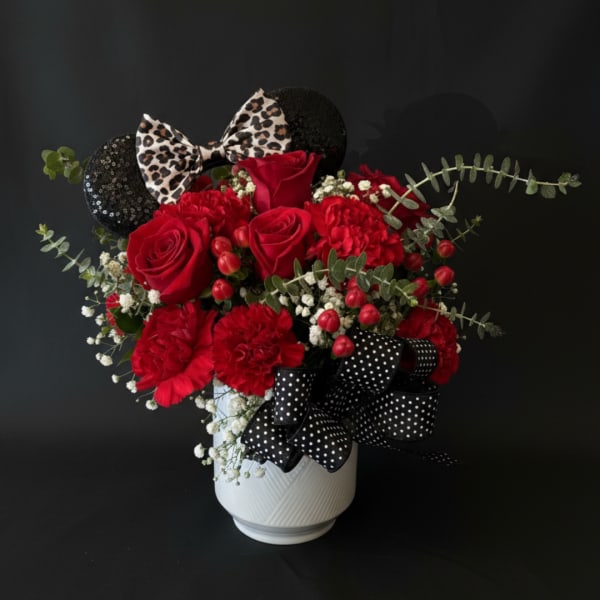 Red roses and carnations in a white vase with black bows