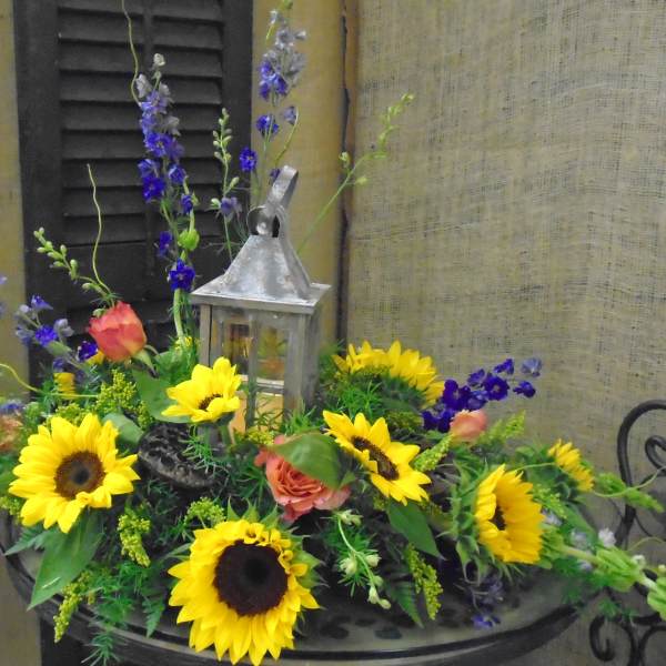 Sunflower arrangement with roses and a lantern centerpiece