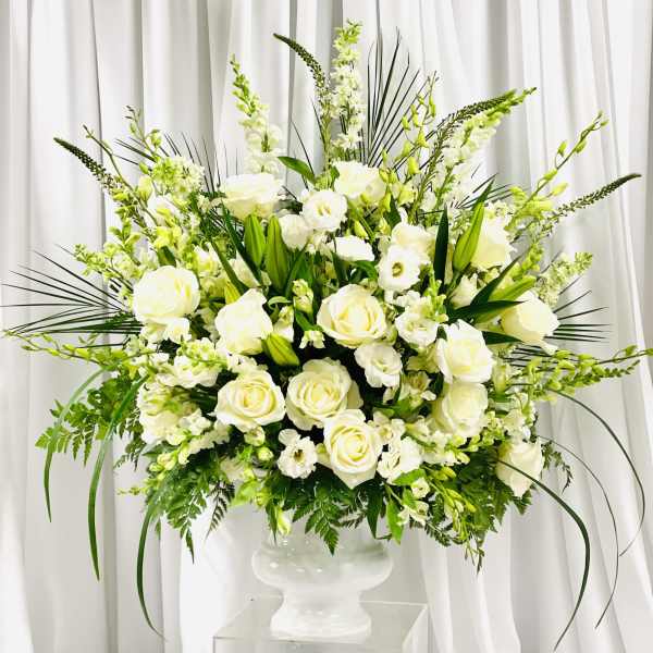 Large white floral arrangement in a pedestal vase