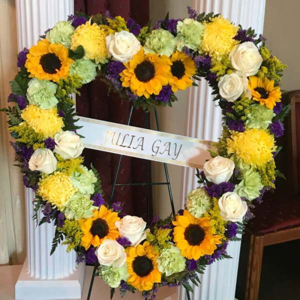 Heart-shaped floral wreath with sunflowers, white roses, and purple accents