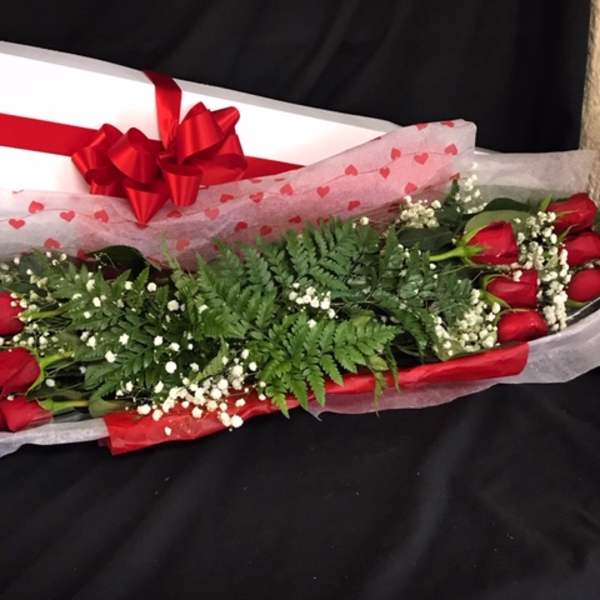 Long bouquet of red roses with baby's breath and a gift box tied with a red bow