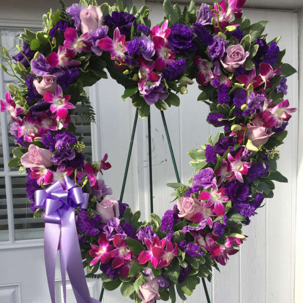 Heart-shaped floral wreath with purple and pink flowers on an easel